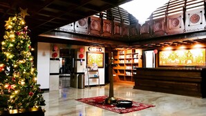 A spacious lobby with a Christmas tree, a reception desk, and a large wooden bookshelf. - Sajjoys Hotel (Varkala)