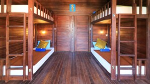 Une cabane en bois avec des lits superposés, chacun étant équipé d’un oreiller et d’une petite table.