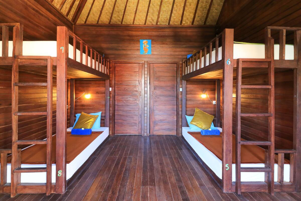Eine Holzhütte mit Etagenbetten, jeweils mit Kissen und einem kleinen Tisch.