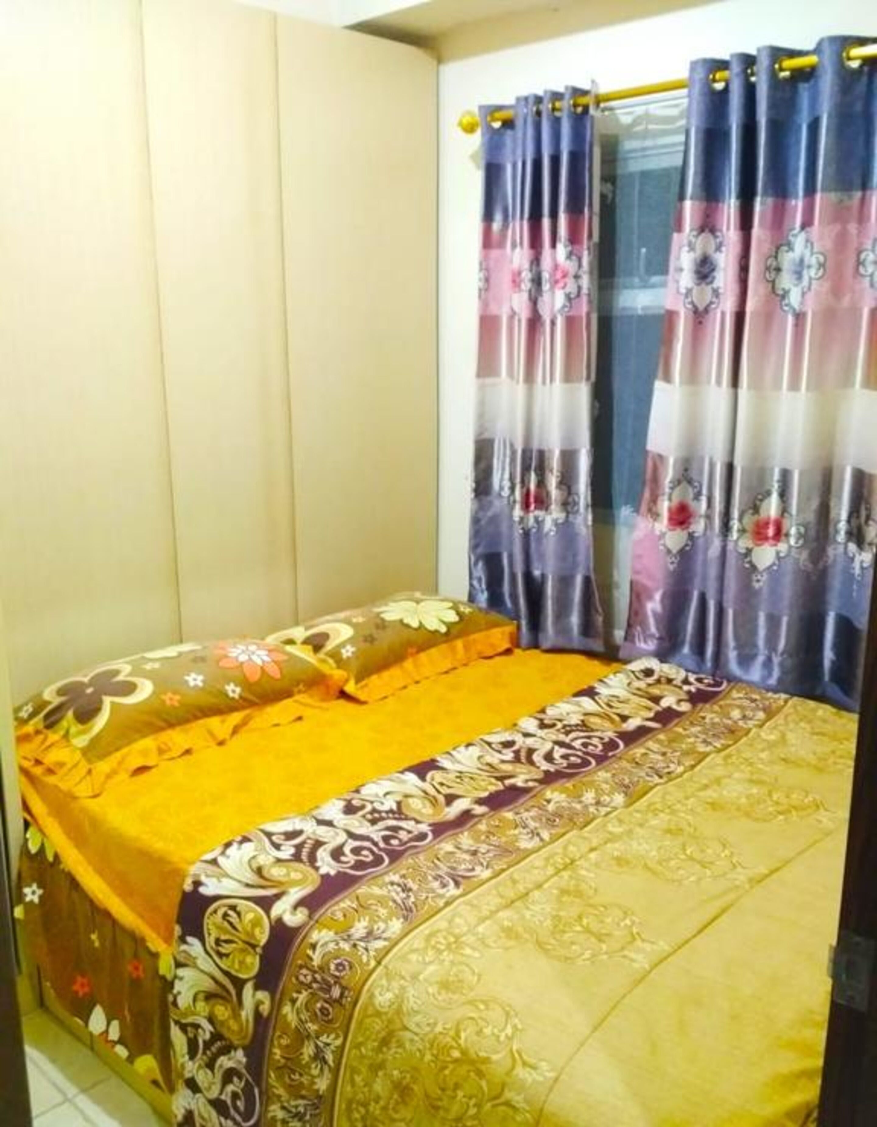A bedroom with a bed, a window with curtains, and a wall with a panel design.