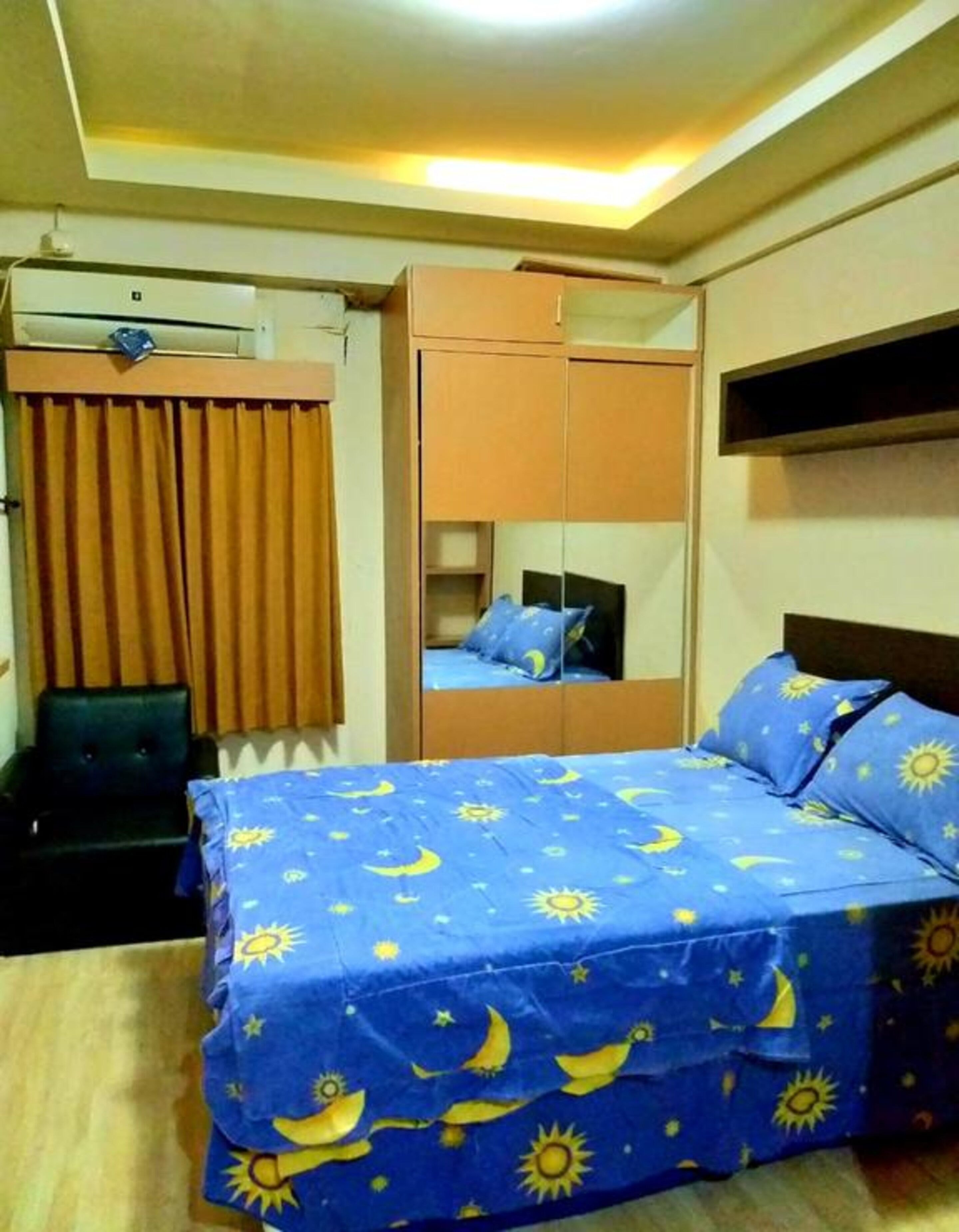 A bedroom with a bed, a wardrobe, a mirror, and a desk.