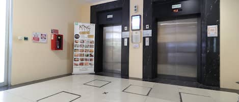 An elevator area with two elevators, a fire extinguisher, and a King logo sign.