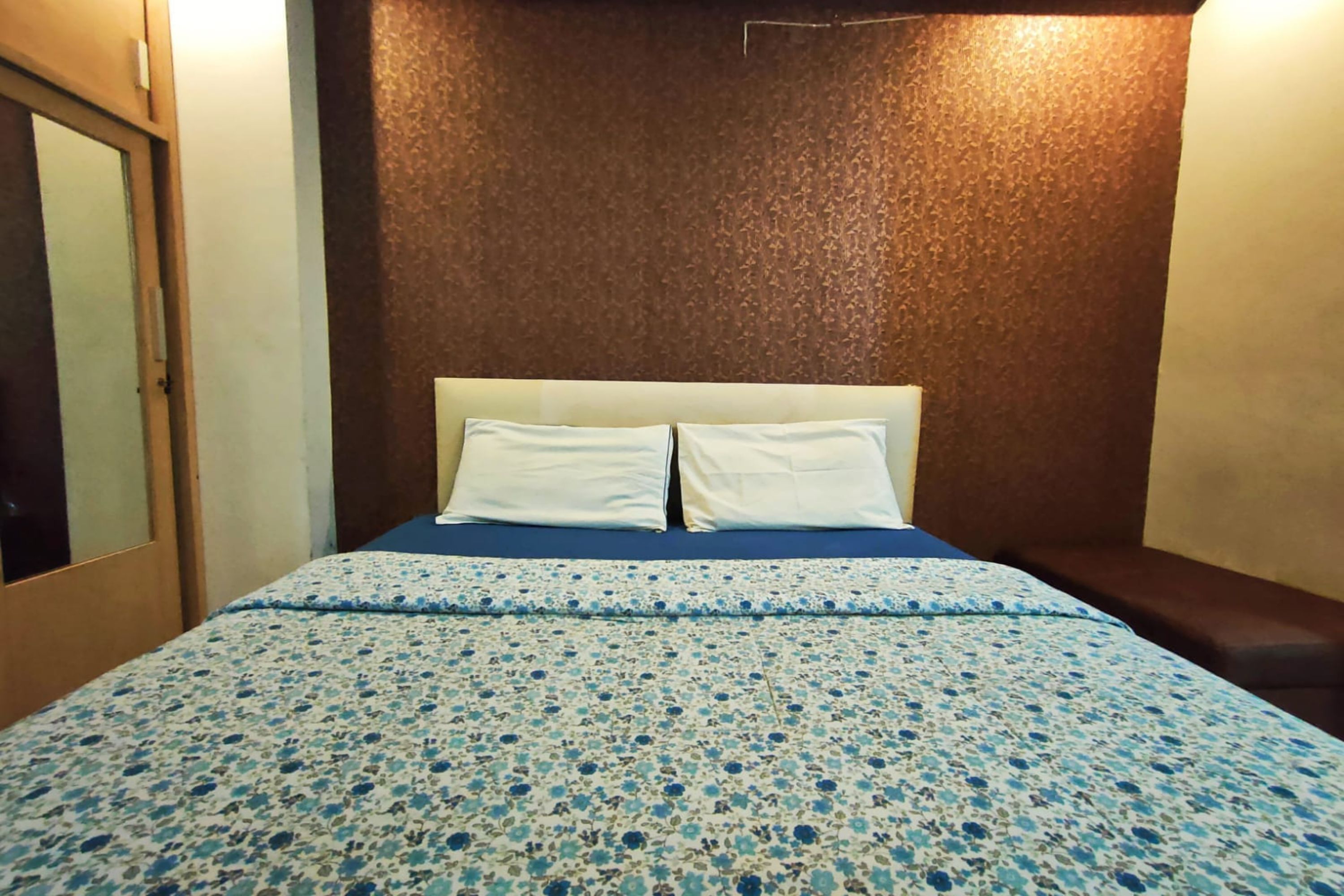 Una habitación con una cama, una puerta de madera y un pared con textura.