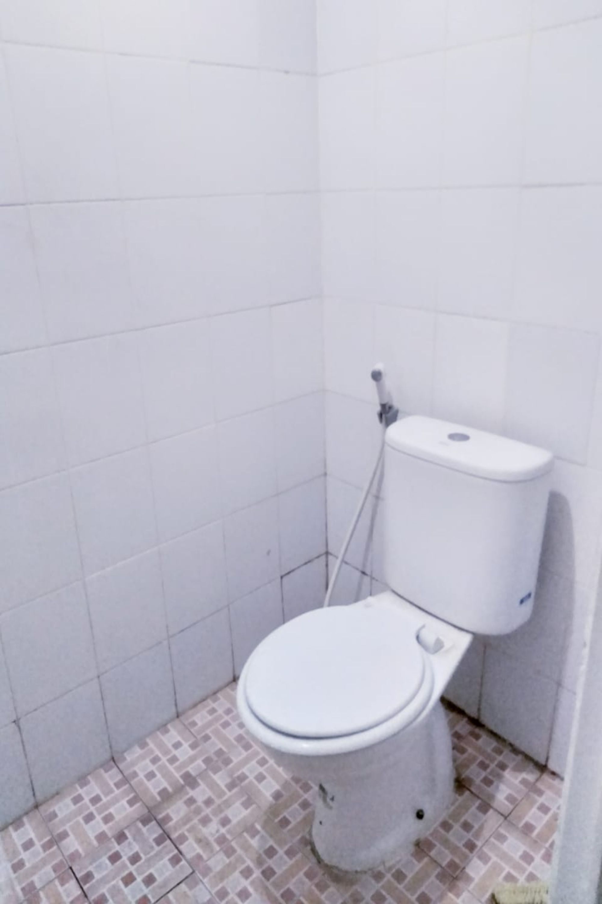 Un baño pequeño con azulejos blancos, un inodoro y una zona de ducha.