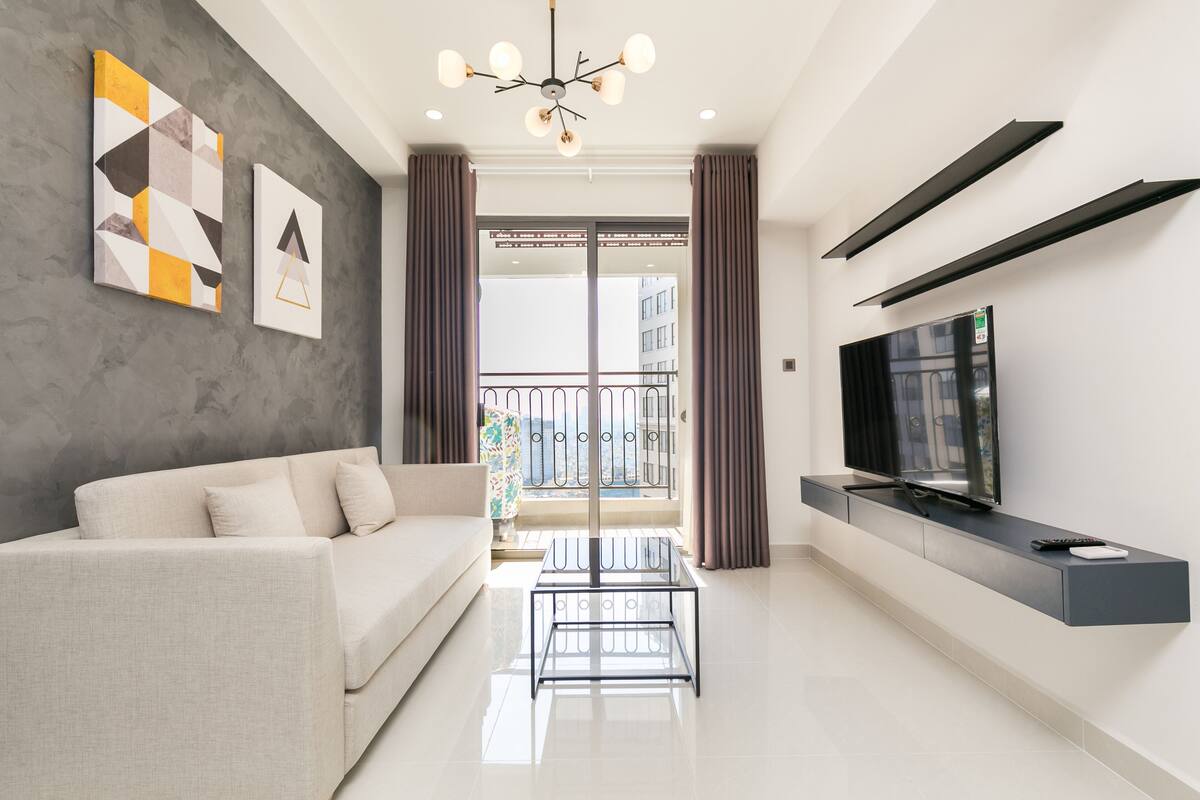A modern living room with a sofa, TV, and artwork on the wall.