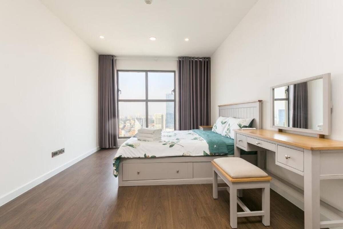 A bedroom with a bed, a desk, a chair, and a window with curtains.
