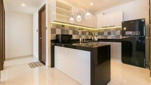 Een moderne keuken met een centraal kookeiland, zwarte apparaten en hanglampen.