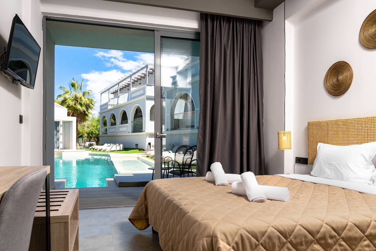 A hotel room with a bed, a TV, a pool view, and a balcony.