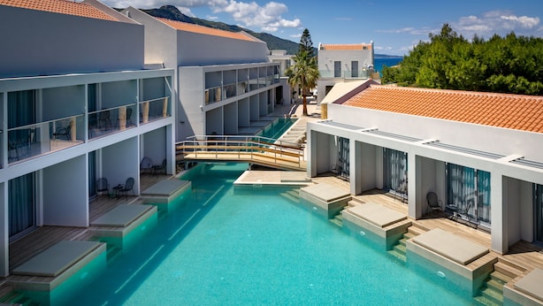 A modern hotel with a central swimming pool, multiple balconies, and a view of the sea. - ArionGreen Riviera (Zakynthos)