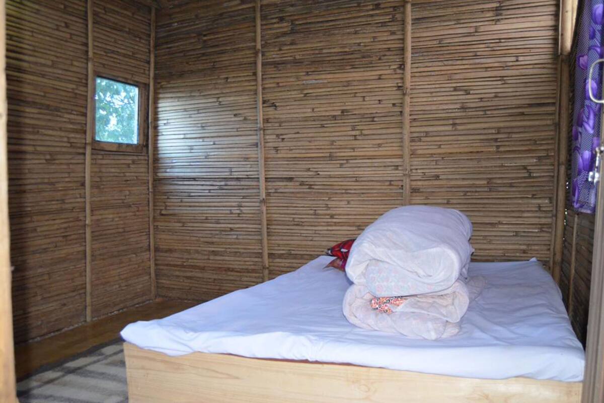 A small, single-bed room with a wooden slatted wall and a small window.