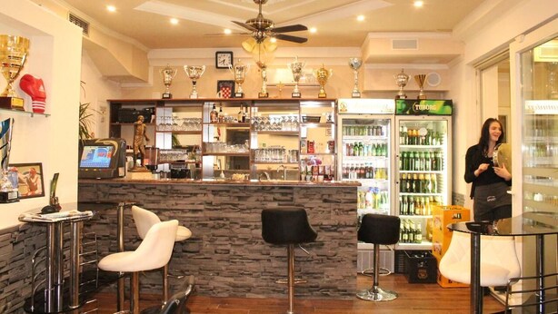 Zona de bar con mostrador de piedra, varios taburetes y un ventilador de techo.