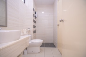 Et moderne badeværelse med hvid vask, toilet og bruseområde.