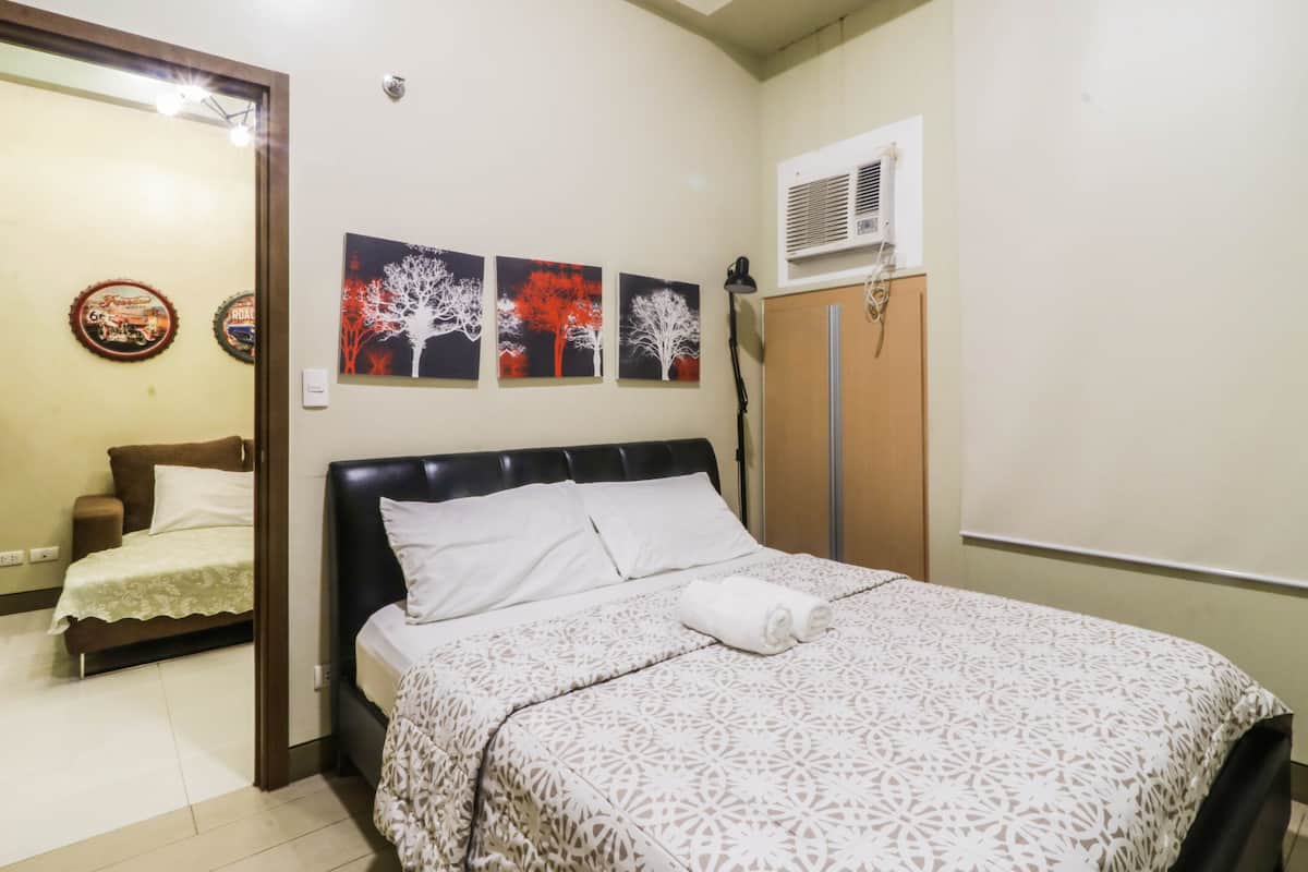 Ein ordentlich eingerichtetes Schlafzimmer mit Bett, Kleiderschrank und Wandbildern.