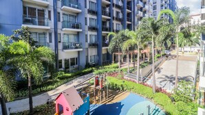 A multi-story residential building with balconies, a playground, and surrounding greenery. - PRS @ One Palm Tree Villa near T3 Airport (Pasay)
