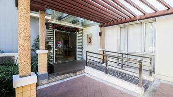 A building entrance with a covered patio, a glass door, and a sign labeled "Cluster D".