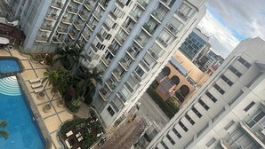 A high-rise residential building with multiple balconies, a swimming pool, and a landscaped courtyard. - PRS @ One Palm Tree Villa near T3 Airport (Pasay)