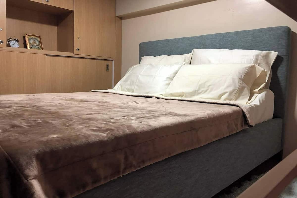 Ein Bett mit Kopfteil, ein Nachttisch und ein Kleiderschrank mit Spiegel.