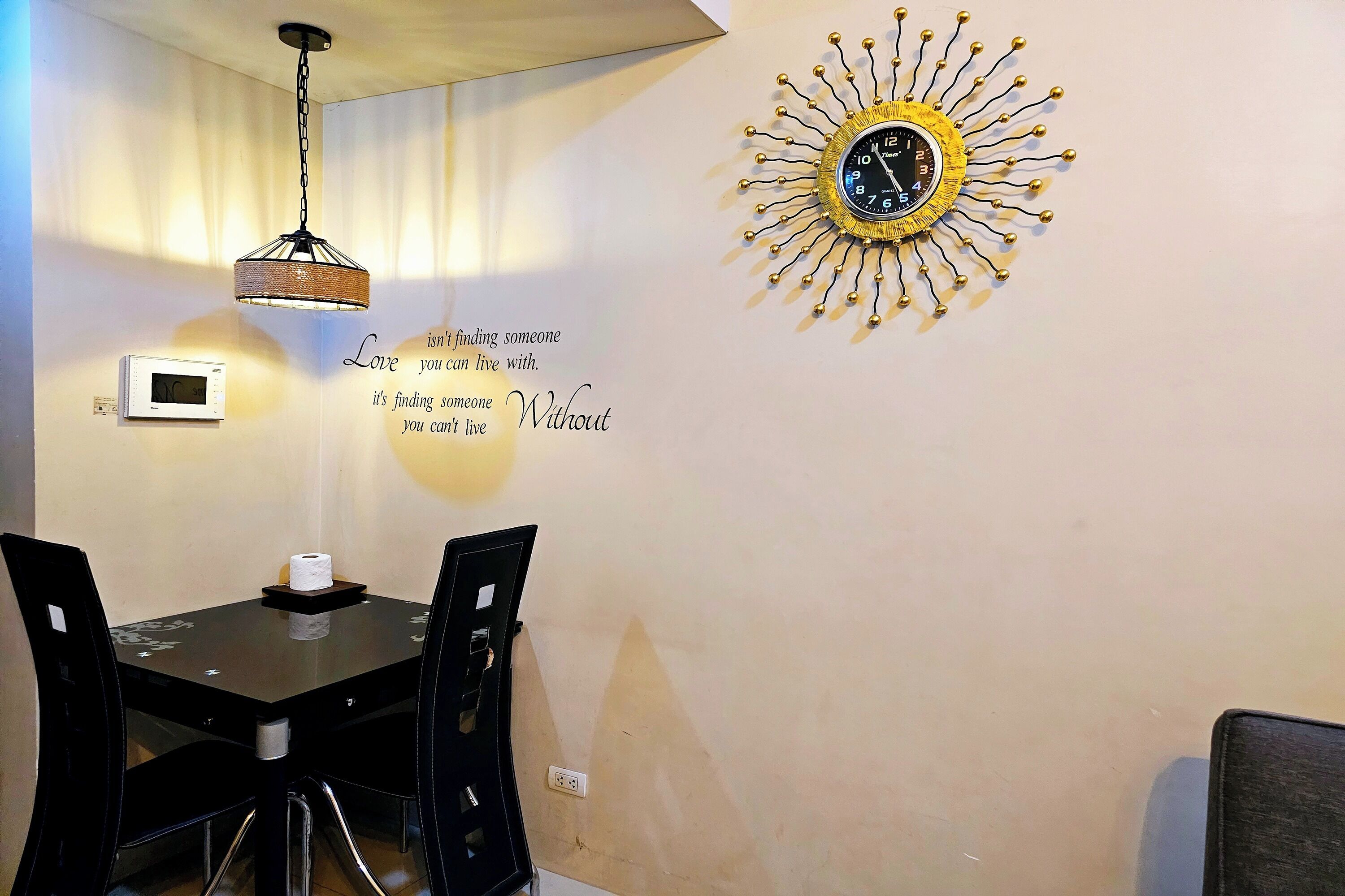 Zona pranzo con orologio rotondo a parete, forno a microonde montato e plafoniera.