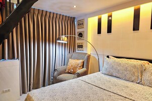 A bedroom with a bed, a chair, a lamp, and curtains.