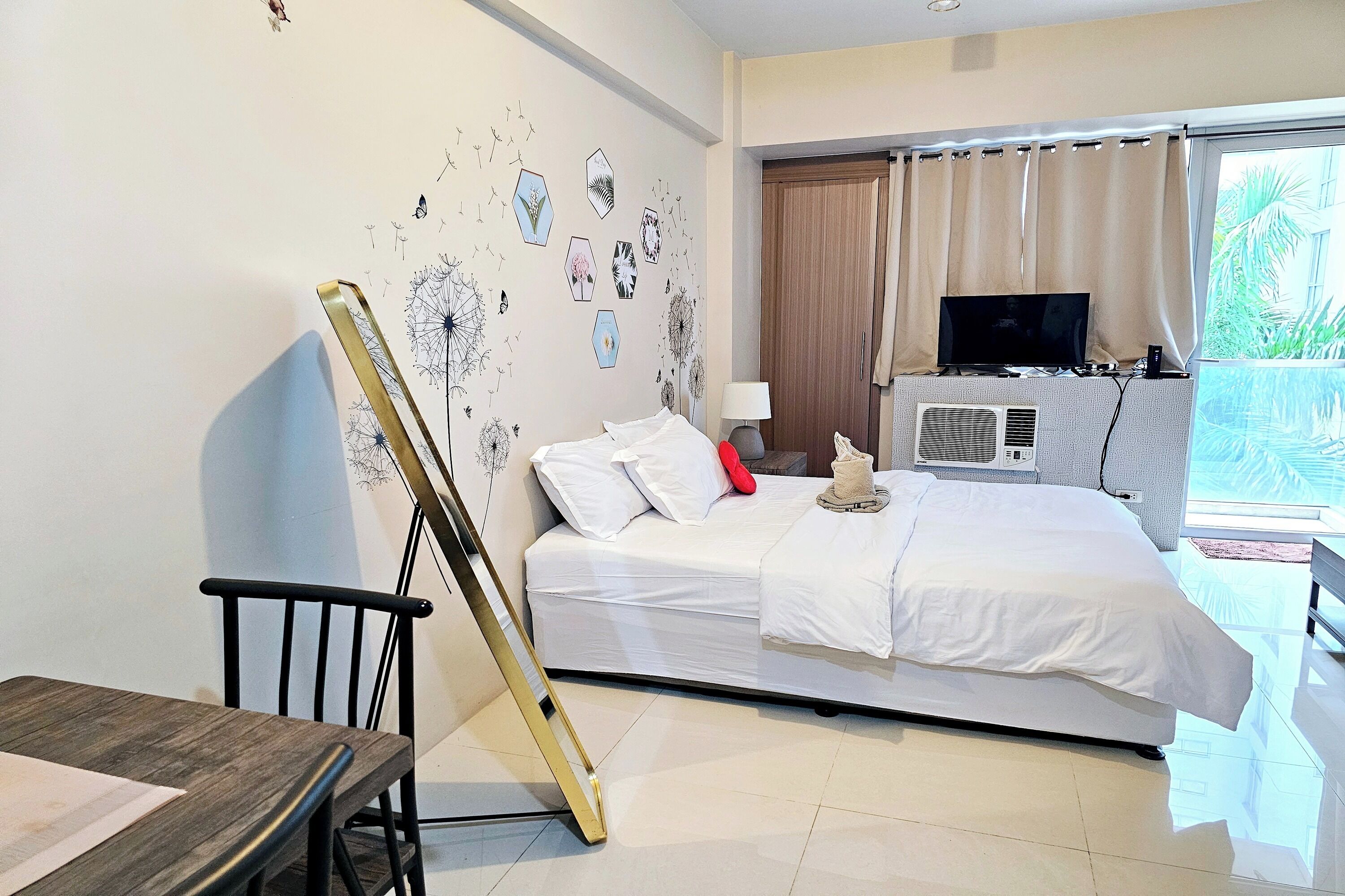 Une chambre d’hôtel avec un lit, une télévision, un bureau et une fenêtre avec des rideaux.