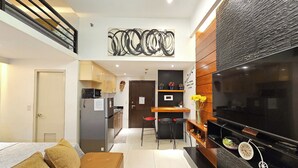 A modern kitchen with a dining area, a sofa, and a TV. - PRS @ One Palm Tree Villa near T3 Airport (Pasay)