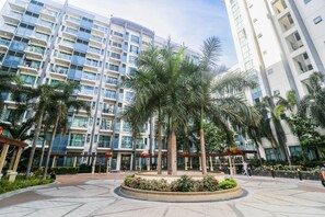 A modern building with multiple floors, large windows, and a central courtyard with palm trees and a circular garden. - PRS @ One Palm Tree Villa near T3 Airport (Pasay)