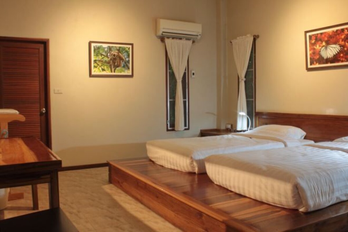 A hotel room with a wooden bed, a small table, and a window with curtains.
