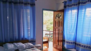 Un dormitorio con cama, cortinas, una puerta de madera y vistas al exterior.