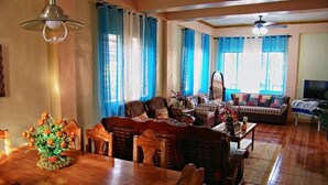 Un salón espacioso con una mesa de comedor de madera, sofás y una televisión.