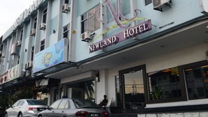 A hotel building with multiple air conditioning units, a sign for 'Newland Hotel', and parked cars in front. - Newland Hotel (Johor Bahru)