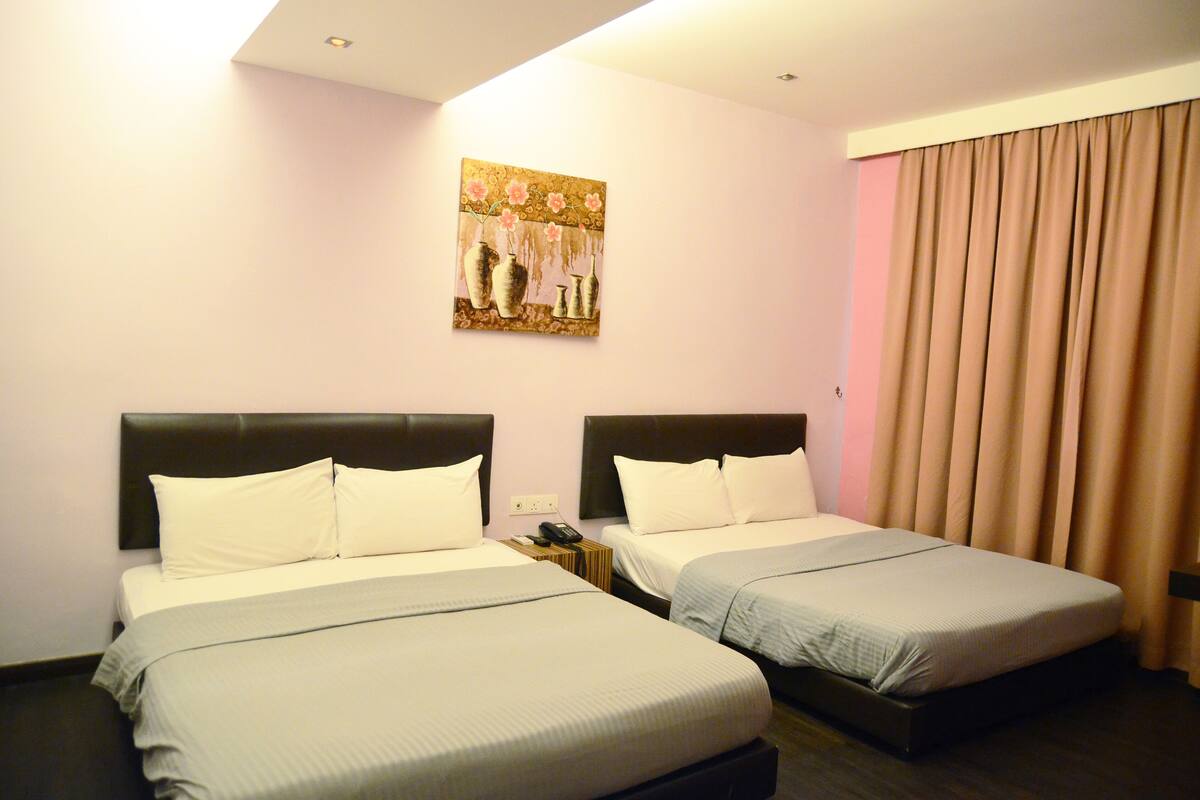 A hotel room with two beds, a painting on the wall, and a curtain on the window.