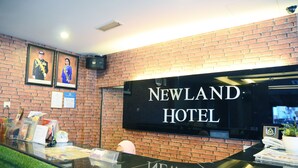 A reception desk with a black sign that reads "NEWLAND HOTEL". - Newland Hotel (Johor Bahru)