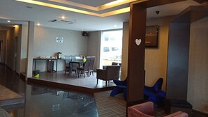 A modern hotel lobby with a dining area, a heart-shaped decoration on a pillar, and a sign indicating a breakfast area. - Newland Hotel (Johor Bahru)