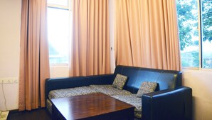 A room with a sofa, a coffee table, and curtains. - Newland Hotel (Johor Bahru)