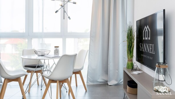 Uma sala de jantar moderna com uma mesa redonda, cadeiras brancas e um lustre.