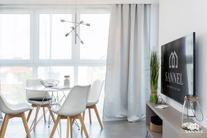 Un espace repas moderne avec une table ronde, des chaises blanches et un luminaire suspendu.