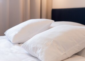 A bed with white pillows and a dark headboard.