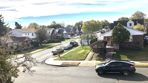 Una calle residencial con casas, coches y cielo despejado.