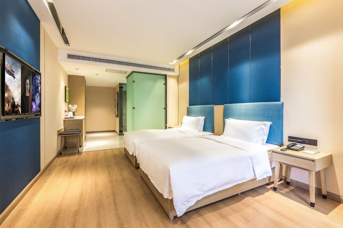 A modern hotel room with a large bed, bedside tables, and a view of the hallway.