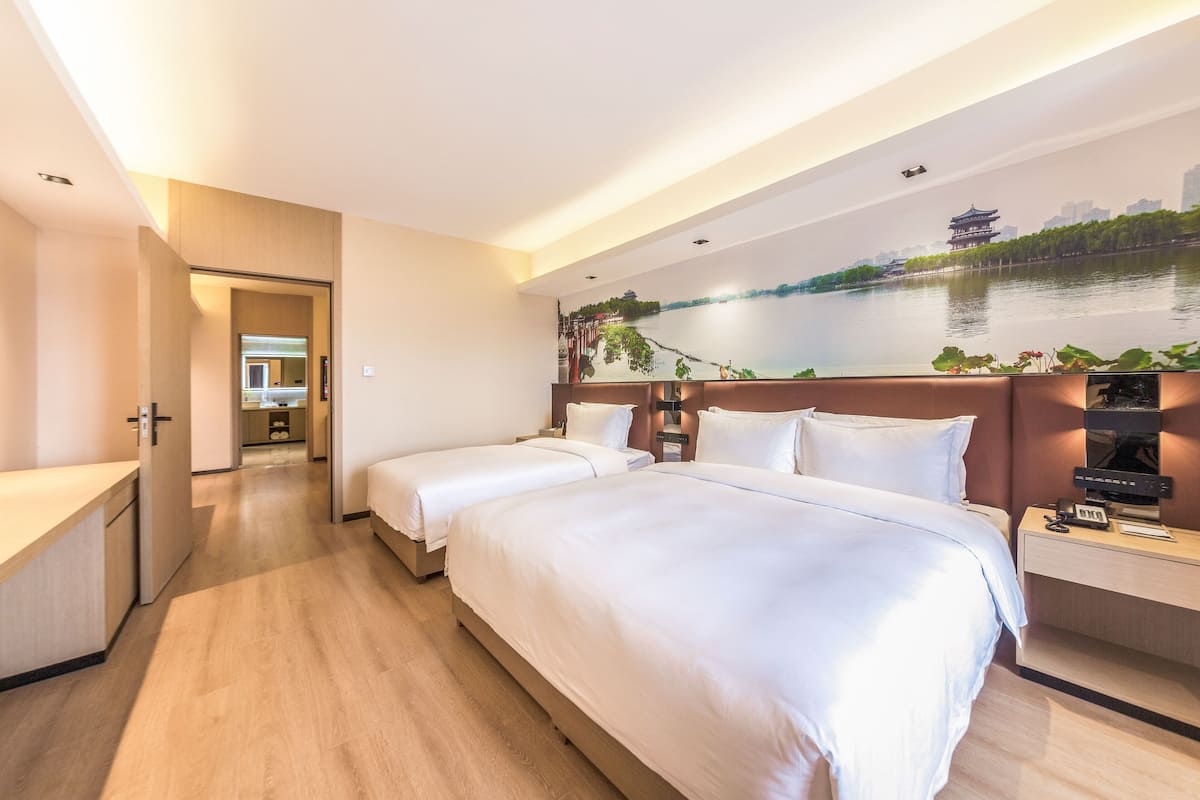 A hotel room with two beds, a view of a river, and a cityscape mural on the wall.