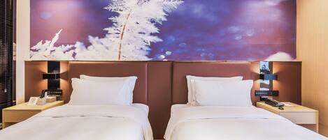 Habitación de hotel con dos camas, una mesita de noche con teléfono y una lámpara de pared.
