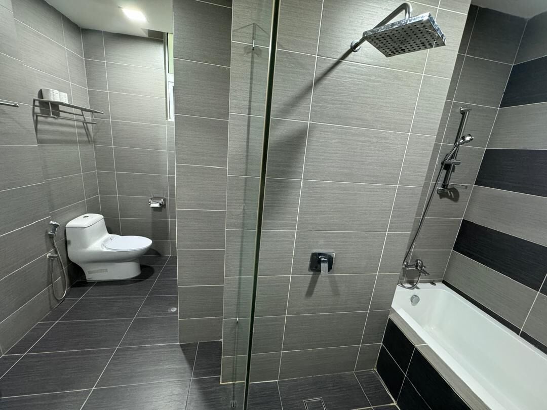 A modern bathroom with a glass-enclosed shower, a toilet, and a bathtub.