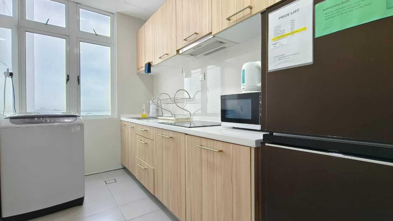 Eine Küche mit Holzausstattung, einer Mikrowelle, einem Kühlschrank und einer Preisliste an der Wand.