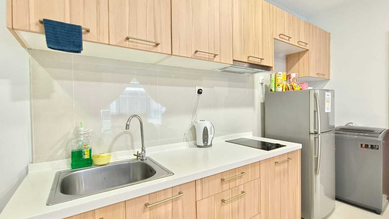 Een moderne keuken met houten kastjes, een roestvrijstalen spoelbak, een waterkoker en een koelkast.