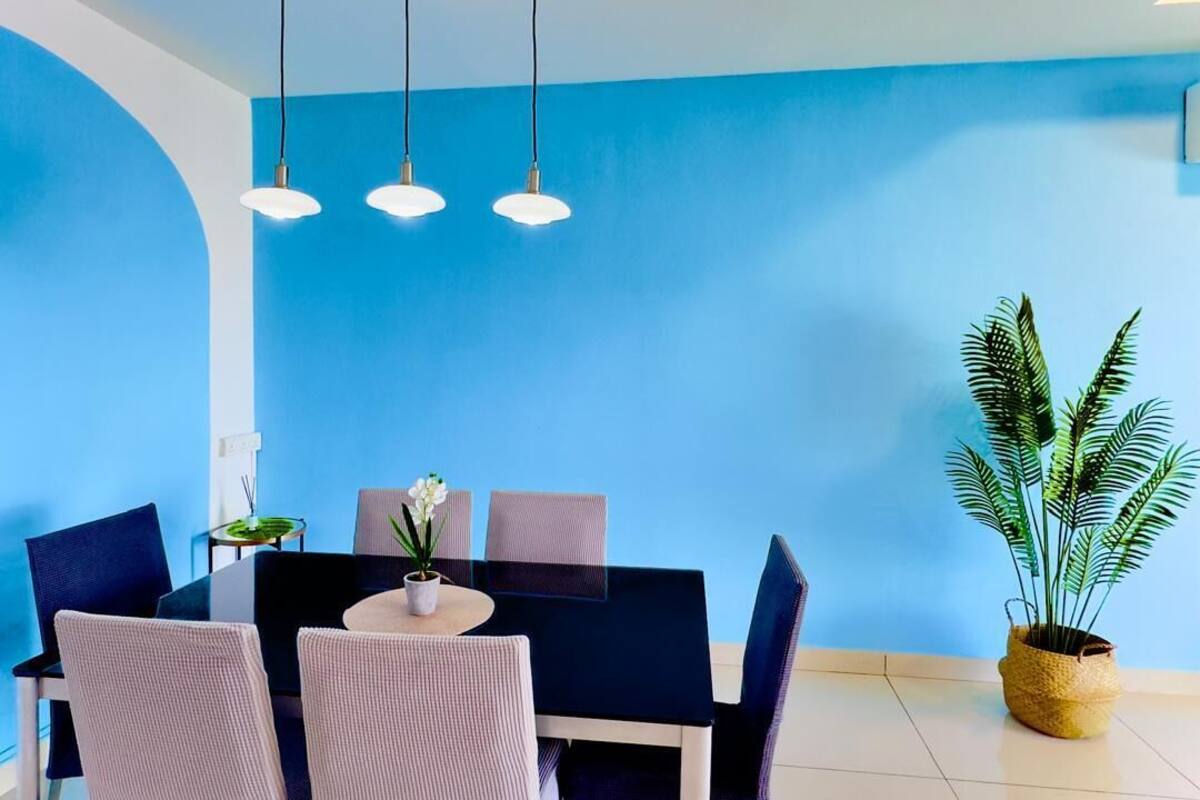 A dining area with a round table, chairs, and hanging pendant lights.