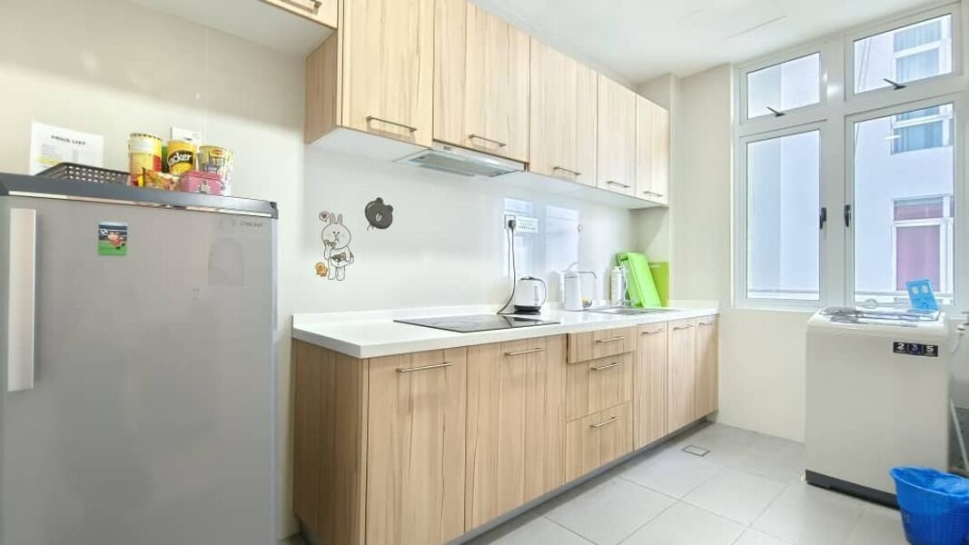 A modern kitchen with wooden cabinets, a refrigerator, a coffee maker, and a small dishwasher.