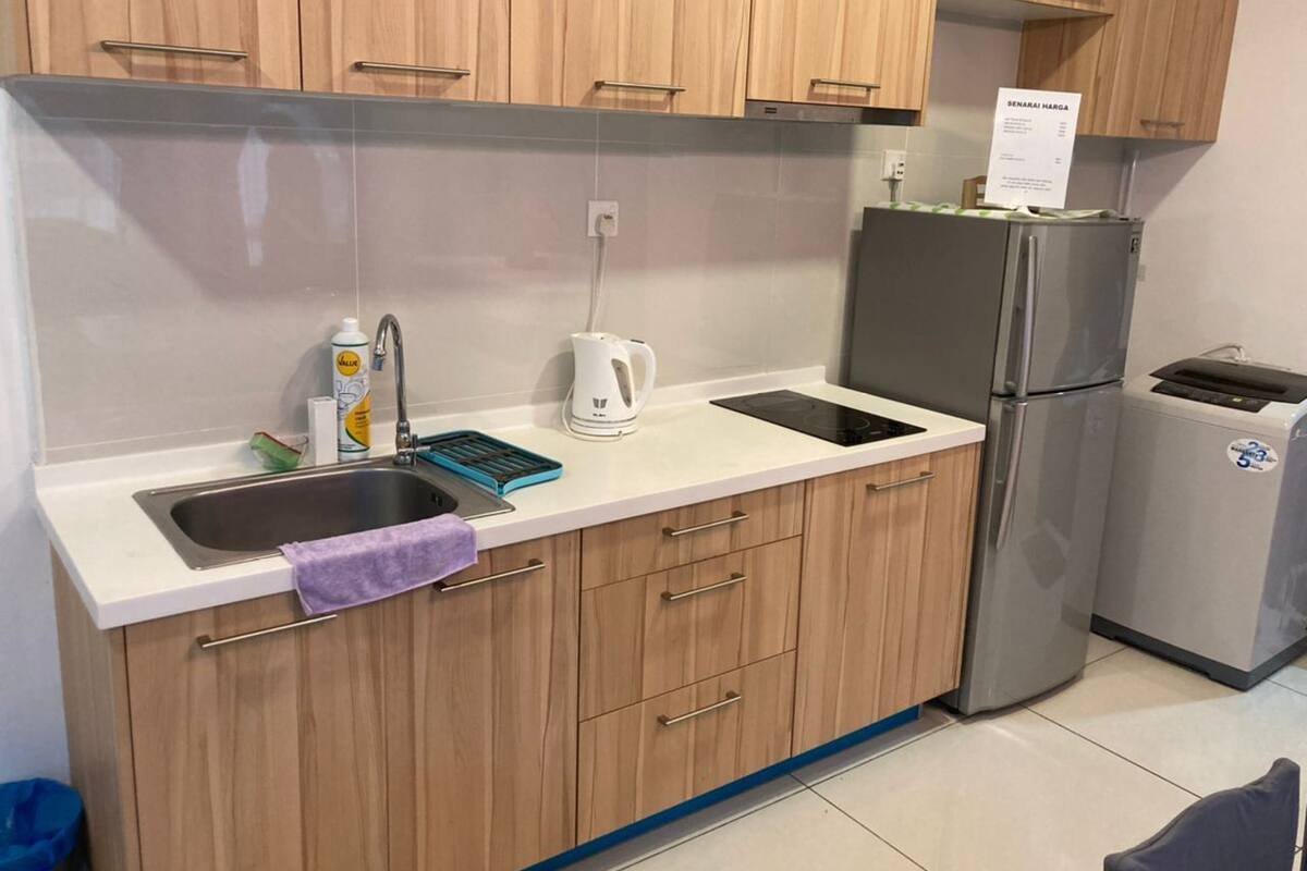 A kitchen with wooden cabinets, a stainless steel refrigerator, a sink, and a coffee maker.