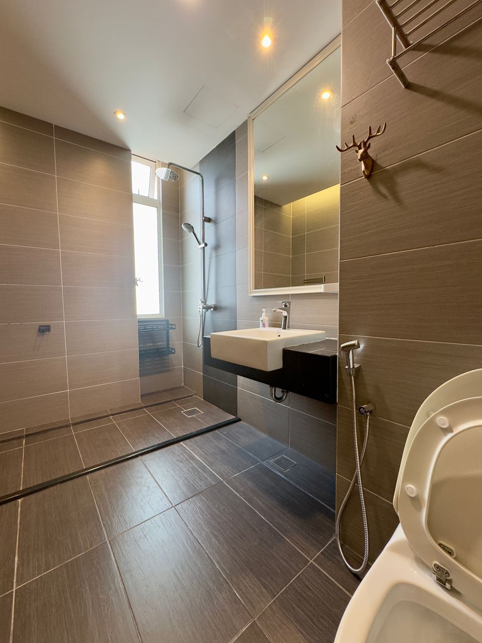 Un baño moderno con ducha a ras de suelo, lavabo con espejo y retrete.
