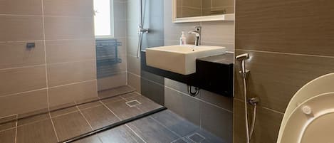 Un baño moderno con ducha a ras de suelo, lavabo con espejo y retrete.