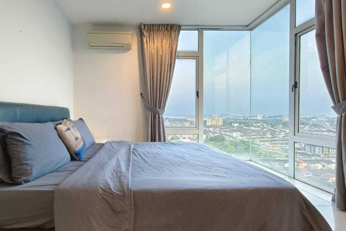 A bedroom with a large bed, a blue headboard, and a city view through a large window.